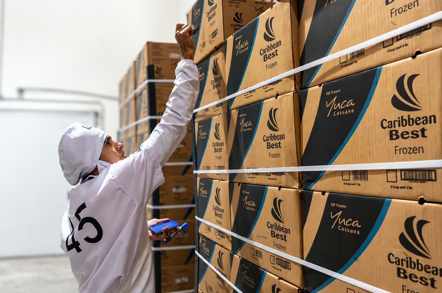Trabajador de Farmers Imports revisando estibas de cajas de yuca congelada Caribbean Best en el cuarto frío